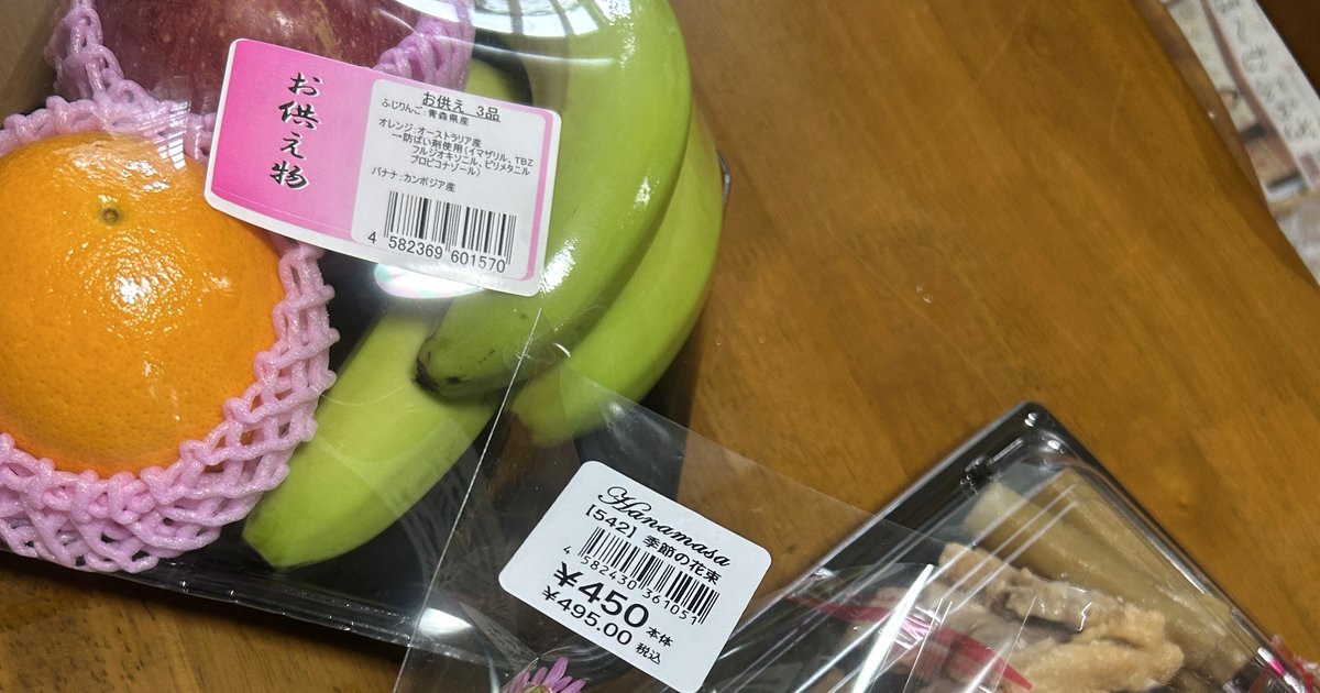 お供え用の果物セットと花束、惣菜のパック