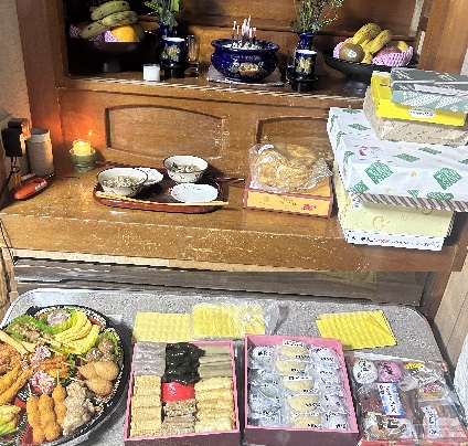 仏壇の前に並べたウークイのお供え。重箱料理と餅、焼き菓子の箱